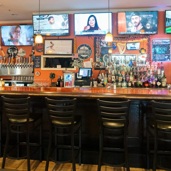 A vibrant bar with multiple TVs, a wide selection of liquor bottles, and beer taps.