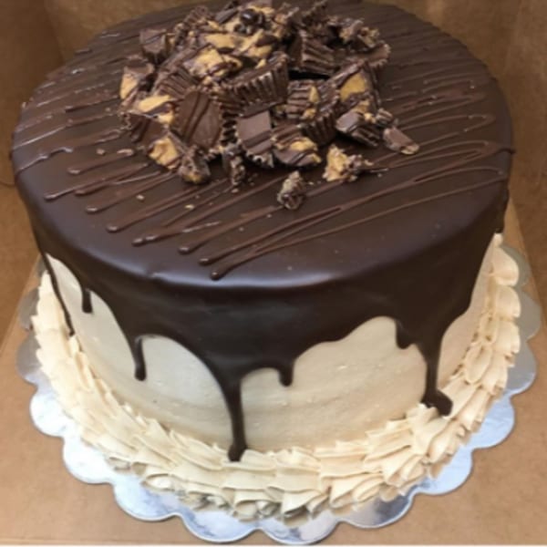 Round cake with chocolate ganache, peanut butter frosting, and chopped peanut butter cups.